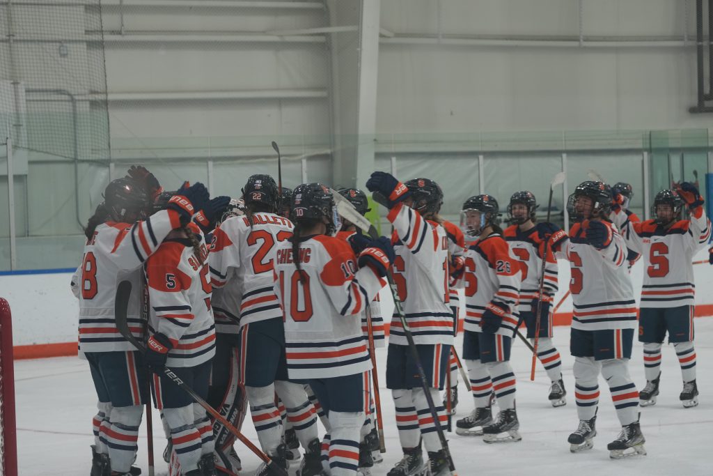 The Orange celebrate as a team. Several of the players are leaving the bench to give Allie Kelley a hug. 